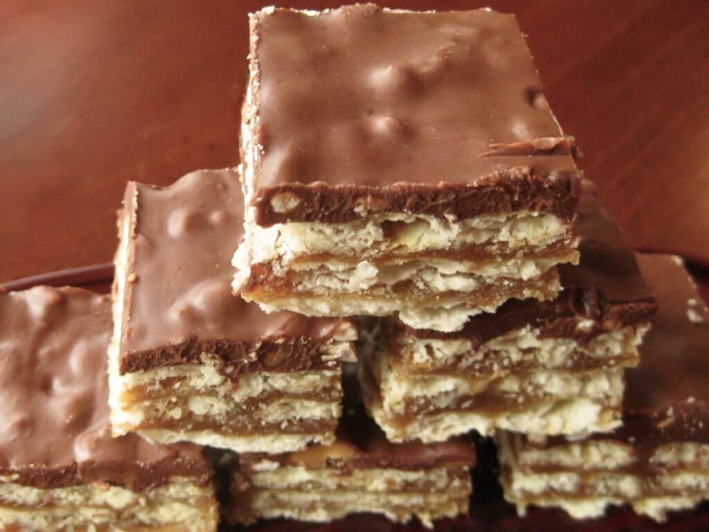 Twickers Bars are stacked on a plate showing their layers of cracker, caramel and delicious topping.