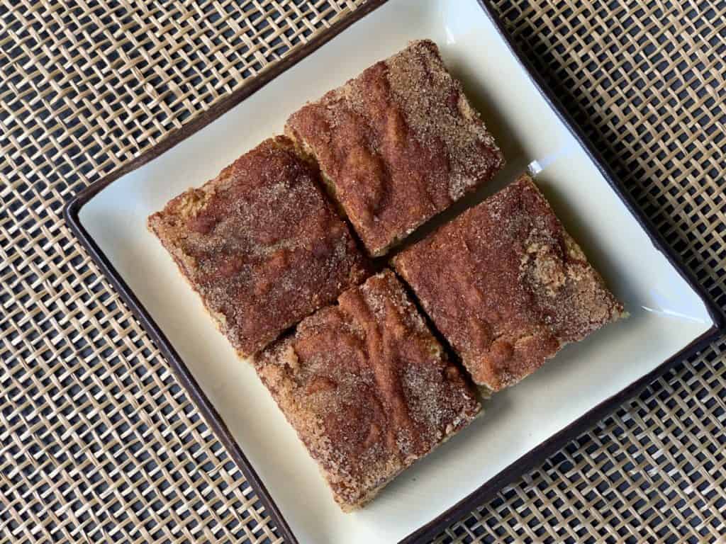 Looking down on Soft Snickerdoodle Blondies topped with cinnamon and sugar on a square plate.