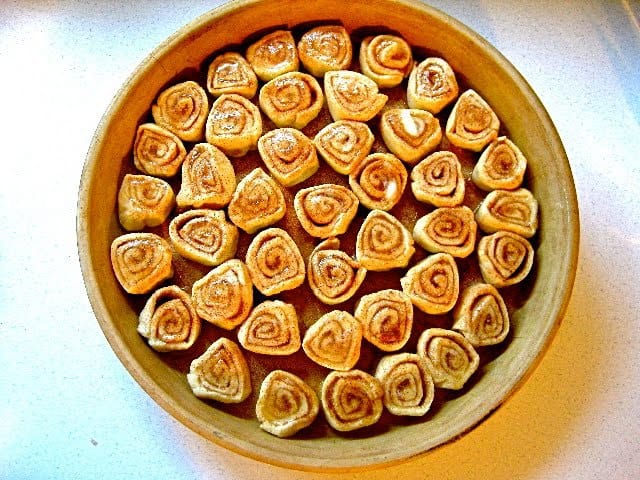 Slices of Cinnamon Roll dough are arranged in a baking dish and ready to put in the oven.