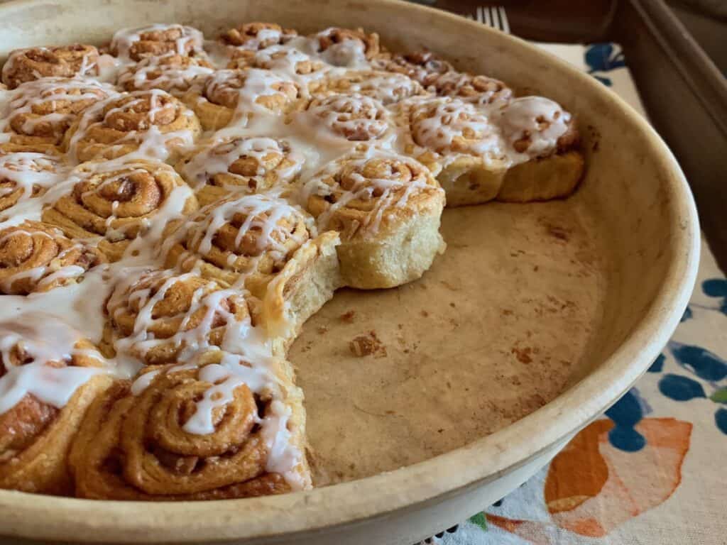 A pan of Quick and Easy Mini Cinnamon Rolls with several rolls missing.