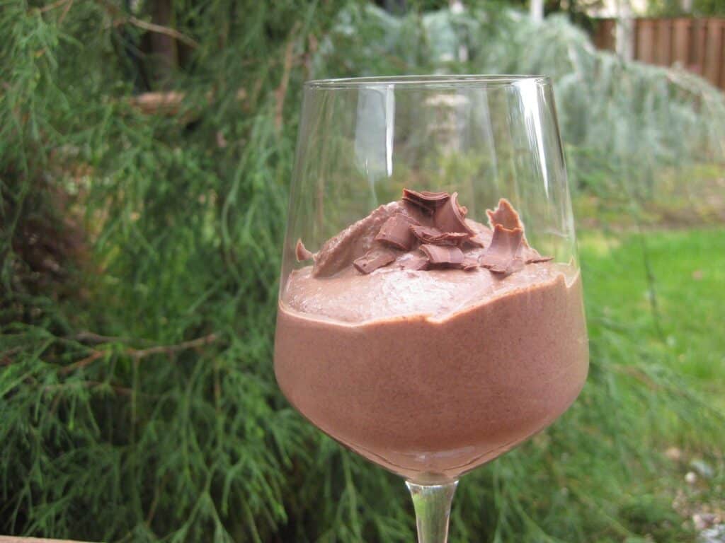 Chocolate Tofu Mousse topped with chocolate curls and served in a stemmer glass in the garden.