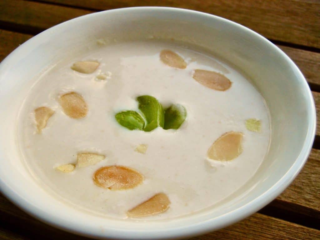 A bowl of White Gazpacho (cold almond and garlic soup), served in a small bowl on a picnic table.