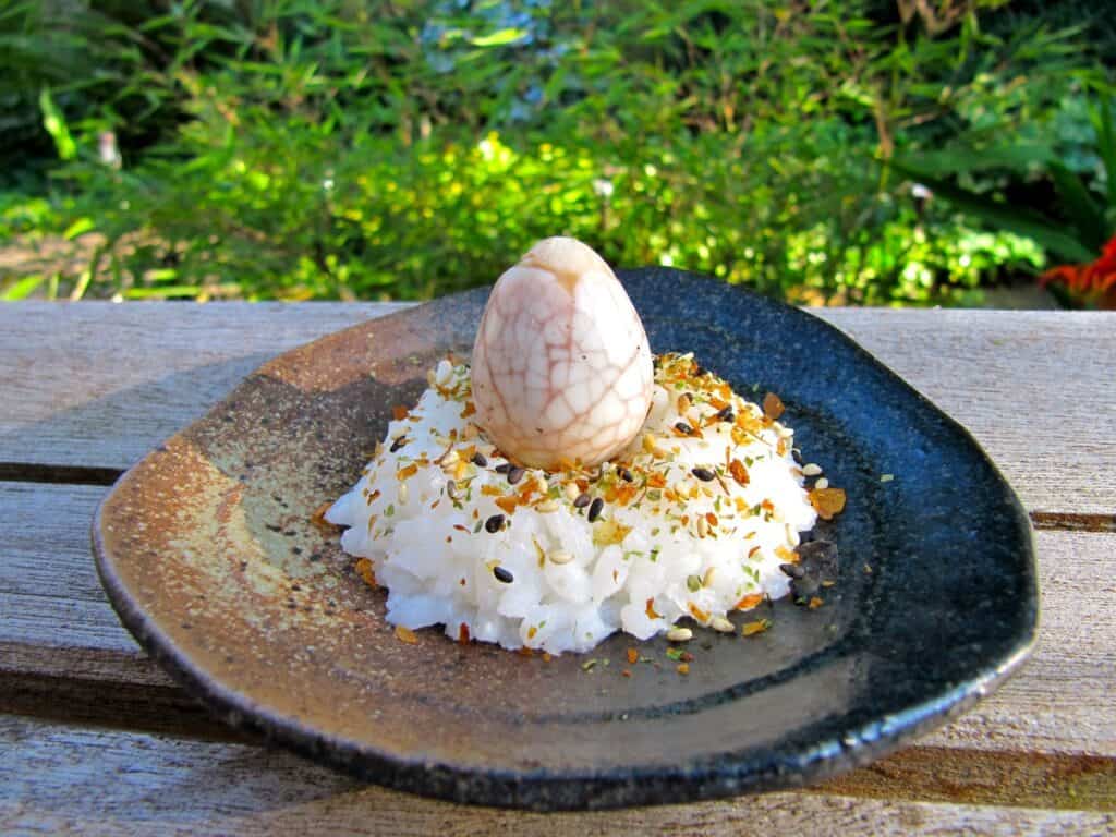 A Sushi Rice Nest topped with a Tea Crazed Quail Egg and sprinkled with furikake.