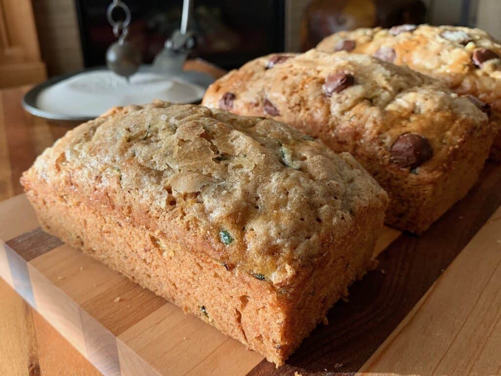 Three loaves of Zucchini Bread on a wood cutting board.