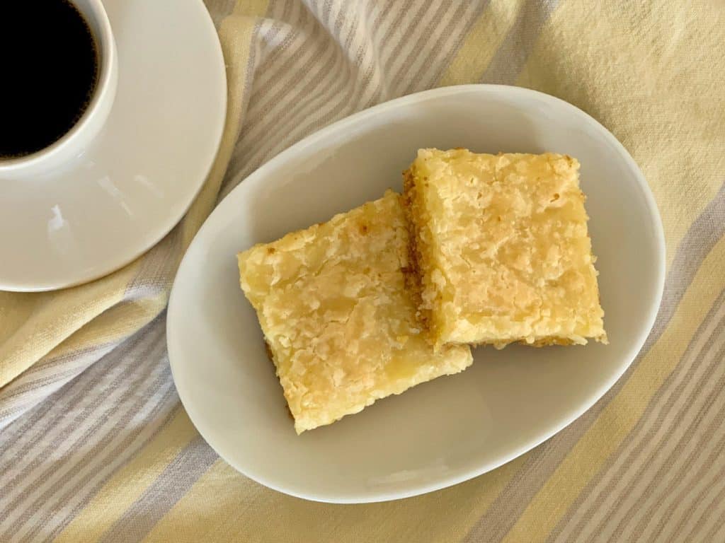Two Chess Squares on a small oval plate beside a cup of coffee.