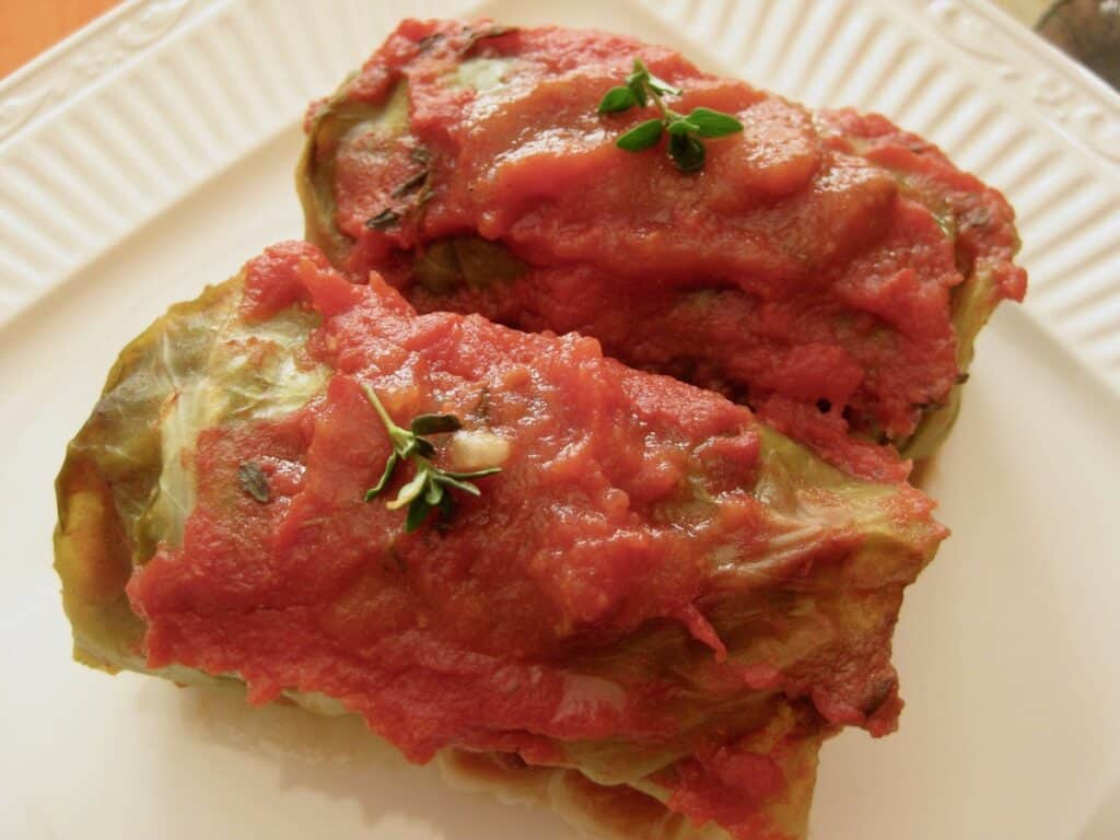 Two Cabbage rolls topped with tomato sauce and thyme from a  pan of Gram's Galumpki.