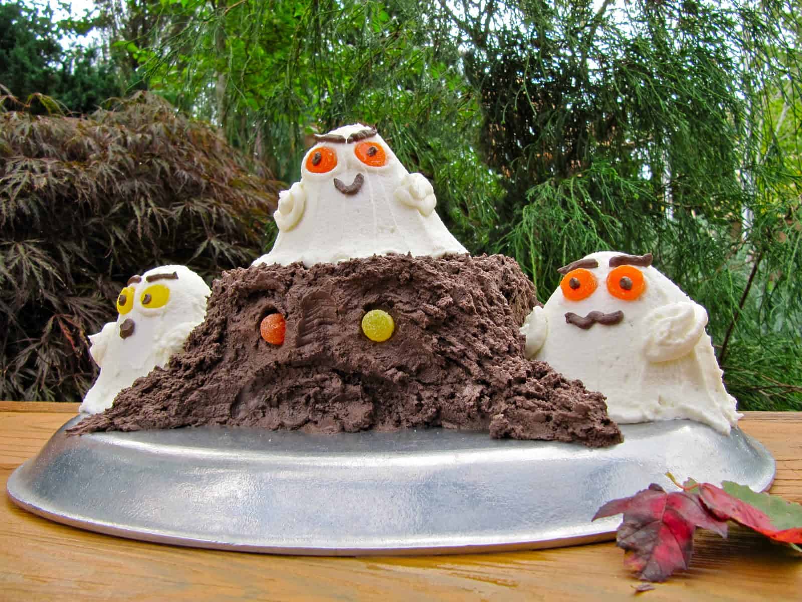 A Decadent Fudge Cake decorated with Buttercream Frosting to make a Haunted Halloween Forest Cake presented in an autumn garden.