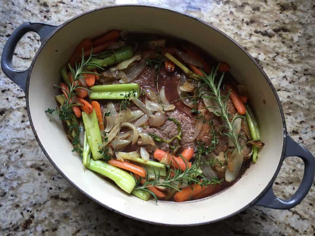 Beef Pot Roast with celery, carrots and herbs and ready to cover and put in the oven.
