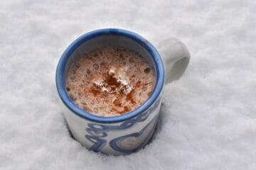 Frothy Spiced Hot Chocolate topped with whipped cream is served in a stoneware mug.