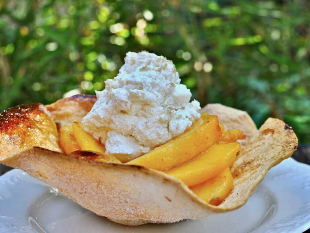Bourbon Spiced Peaches arranged in a cinnamon sugar baked tortilla shell topped with whipped cream