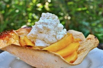 Bourbon Spiced Peaches arranged in a cinnamon sugar baked tortilla shell topped with whipped cream