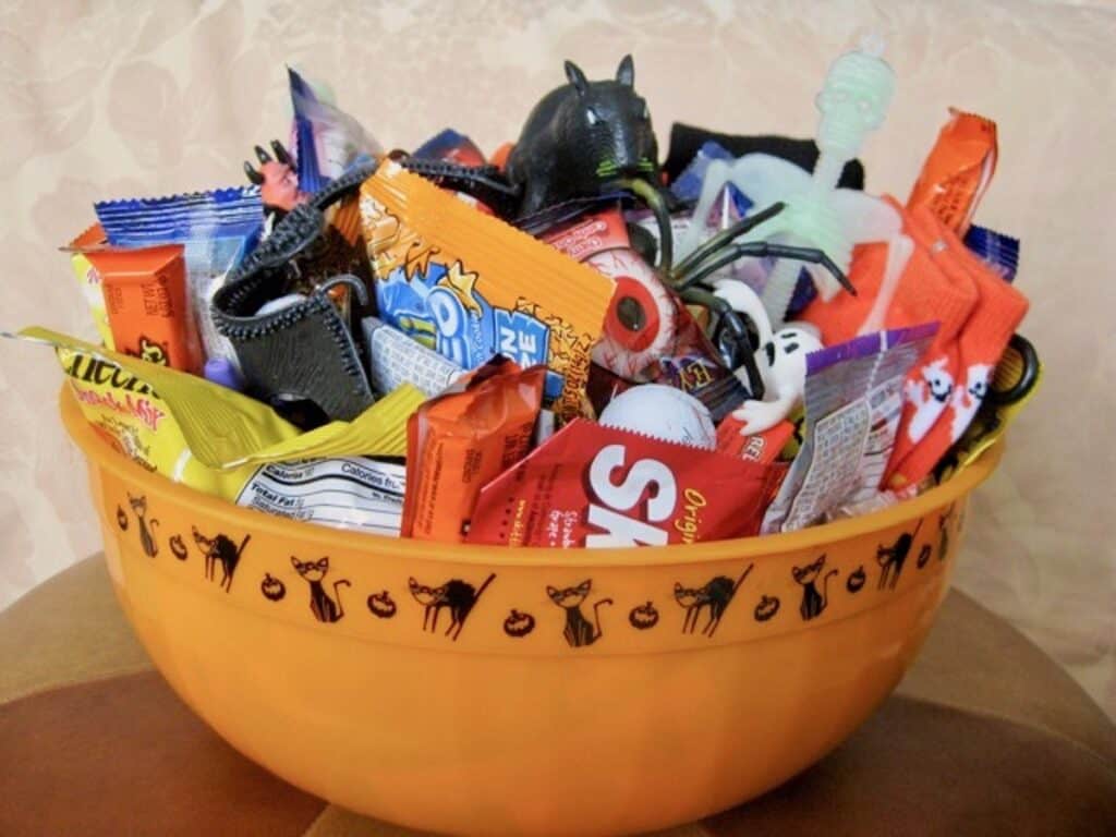 A "Spoiling Bag" of candy, seasonal socks and Halloween favors arranged in a Halloween themed bowl.