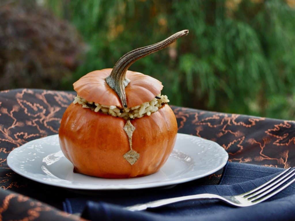 Roasted Mini Pumpkin stuffed with rice and on a plate, served with a fork.