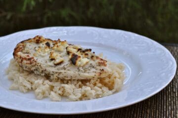 Greek Feta Chicken on a bed of rice served on a white plate.