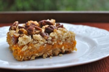 Spirited Southern Sweet Potato Bars with toasted pecan topping on a white dessert plate in the garden.