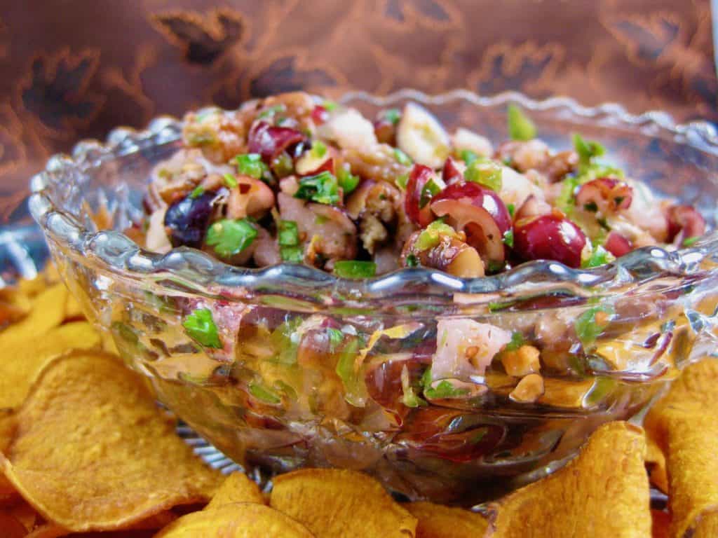 Cranberry Salsa in a glass serving dish surrounded by Baked Sweet Potato Chips. 