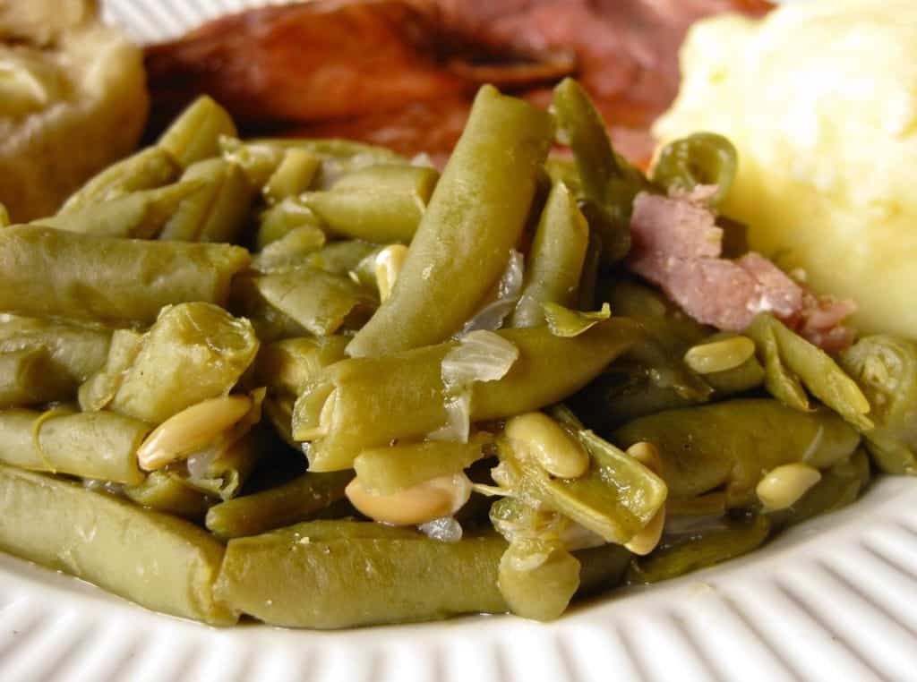 Southern Style Green Beans with bits of onion and ham served as a side dish on white plate.