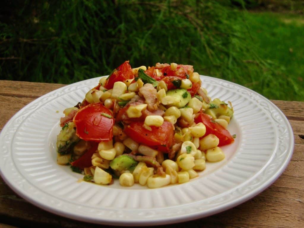A serving of Fried Corn Salad with tomatoes and avocado on a small plate.