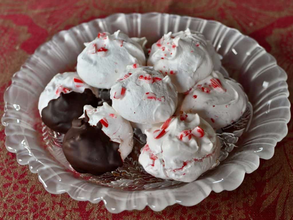 Peppermint Dream Meringue Cookies stacked on a ruffled glass plate.