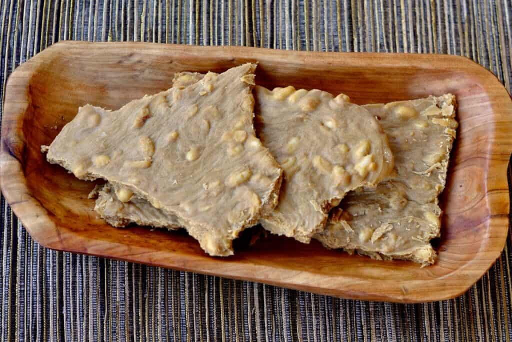 Large Pieces of Scrumptious Soft Peanut Brittle displayed on a wood tray.
