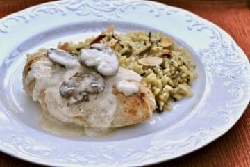 Chicken Breasts with Champagne Sauce is served with a rice pilaf on a white plate.