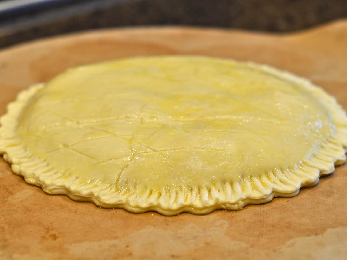 Cover the Almond Cream with a second circle of pastry cut like the first. Press the edges together firmly. Brush the top with the beaten egg and score with a design.