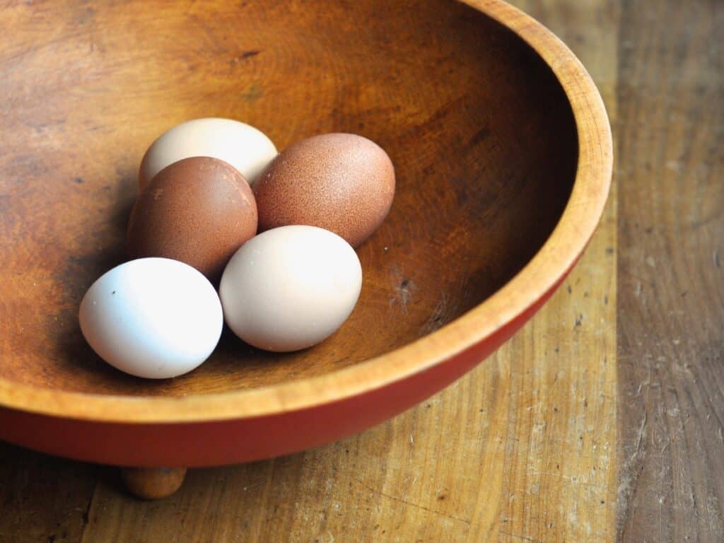 Fresh eggs resting in a wooden bowl.