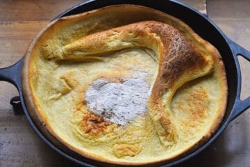 Snickerdoodle Pancake in Cast Iron Skillet with a powdered sugar heart dusted on top.