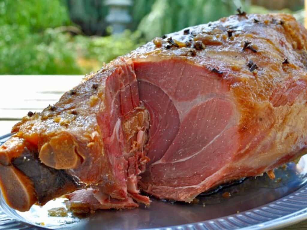 A Kentucky Country Ham studded with cloves and topped with a brown sugar glaze is carved and ready to enjoy.