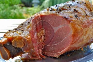 A Kentucky Country Ham studded with cloves and topped with a brown sugar glaze is carved and ready to enjoy.
