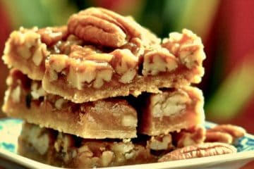 Easy Pecan Bars stacked on a plate with a pecan garnish.