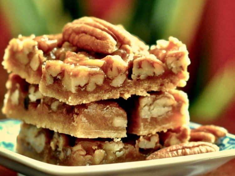 Easy Pecan Bars stacked on a plate with a pecan garnish.