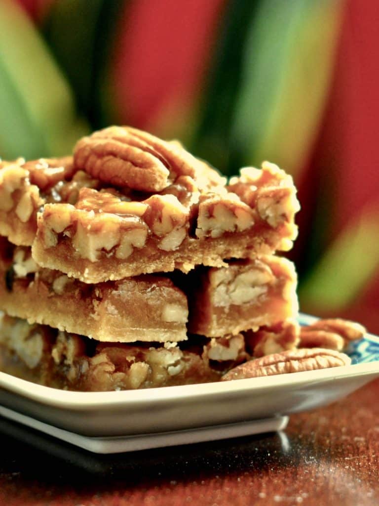 Easy Pecan Bars stacked on a plate with a pecan garnish.