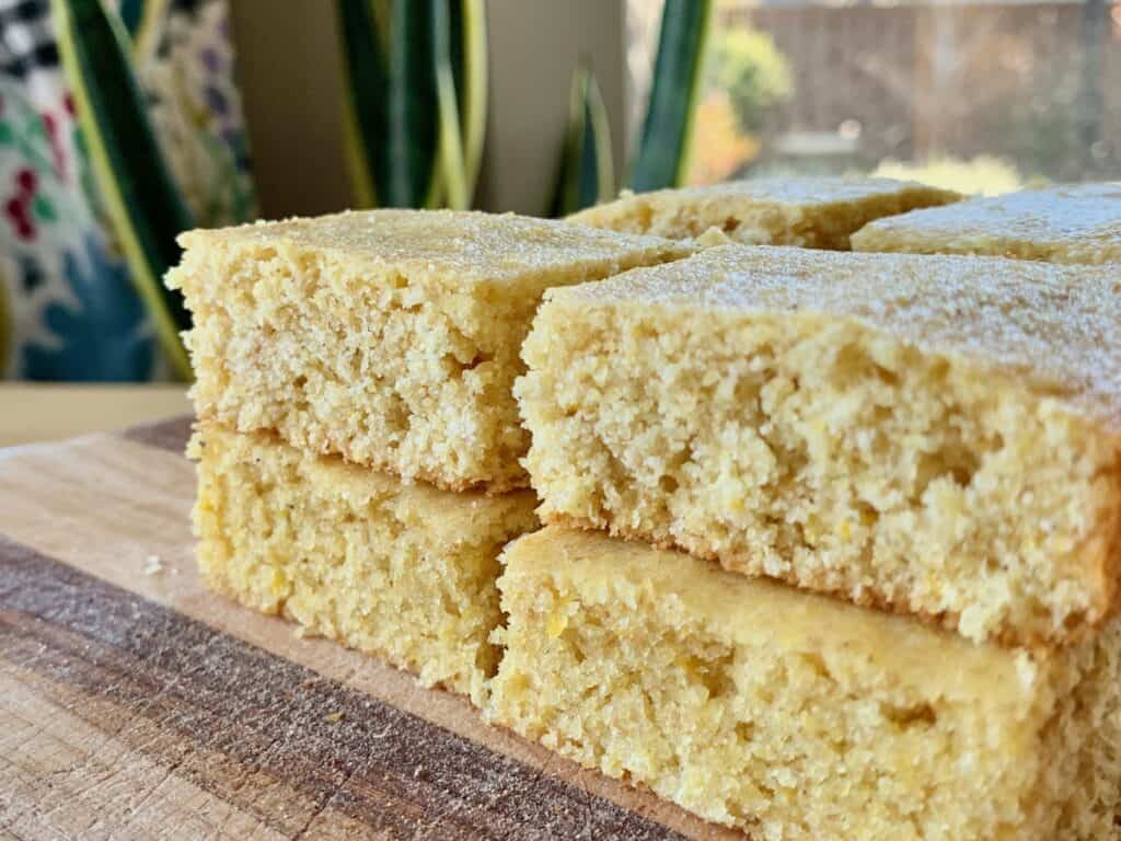 Slices of Back to Basics Cornbread stacked on a wooden cutting board.