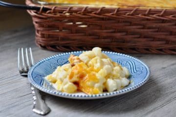 A serving of Hominy Au Gratin Casserole served on a small blue plate beside a serving basket