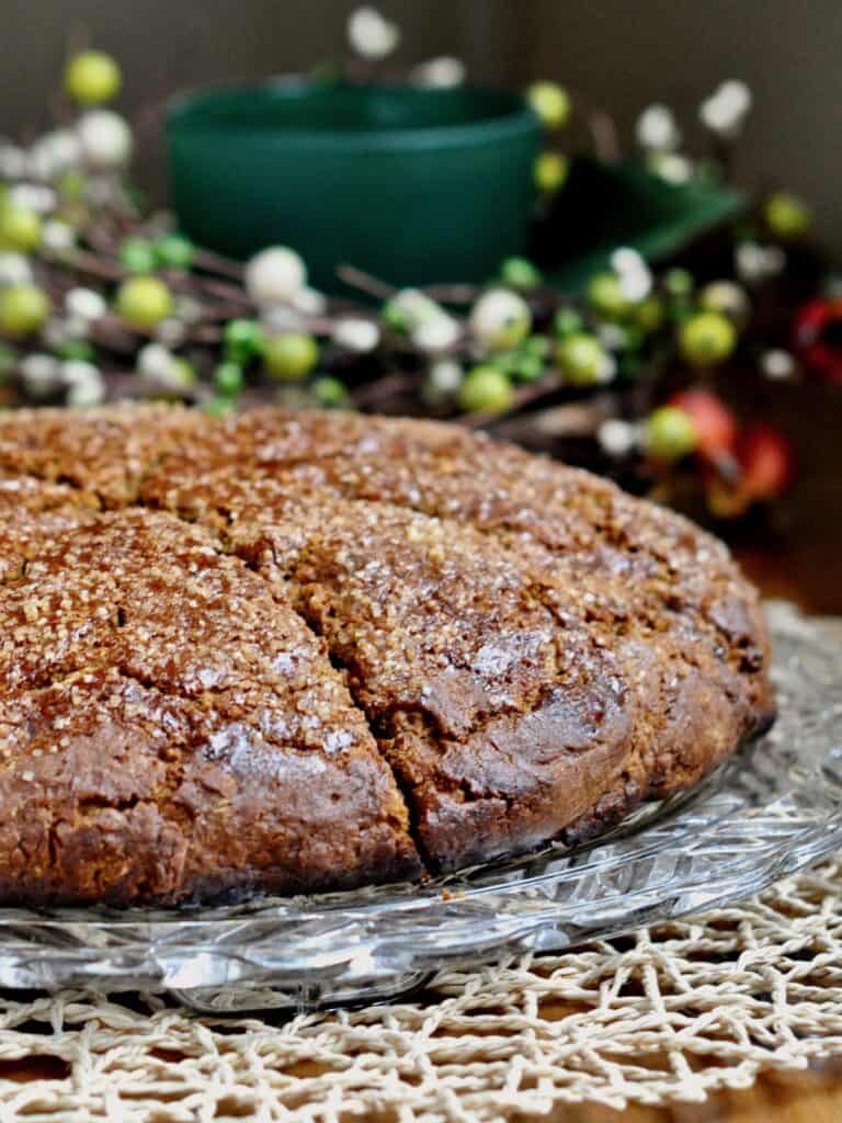 Gingerbread Scones served on a glass platter with a holiday wreath in the background. 