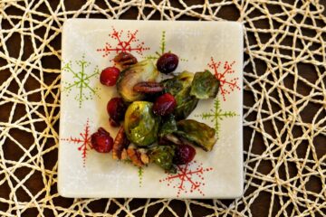 Roasted Brussels Sprouts with Cranberries and Pecans on a small square snowflake plate.