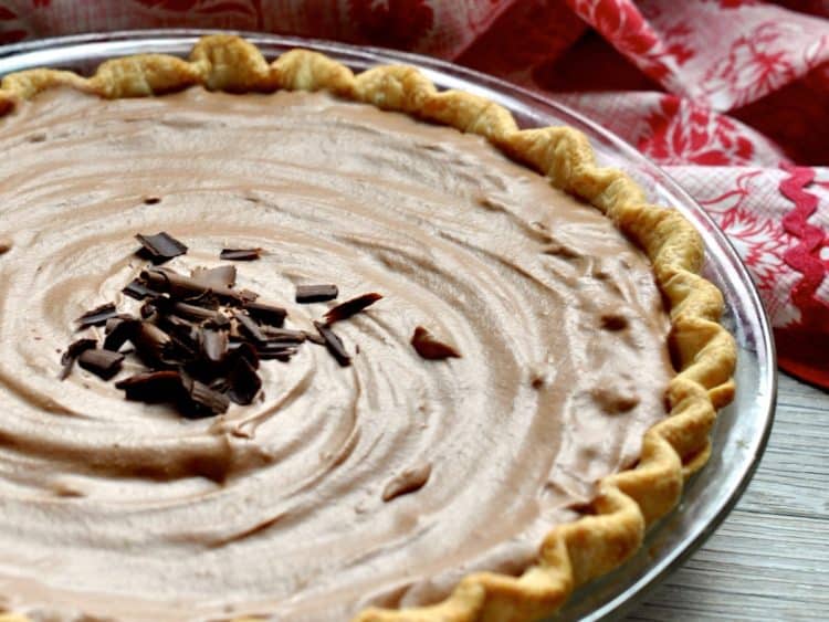 Aunt Hen's Chocolate Bar Pie topped with chocolate curls beside vintage apron.