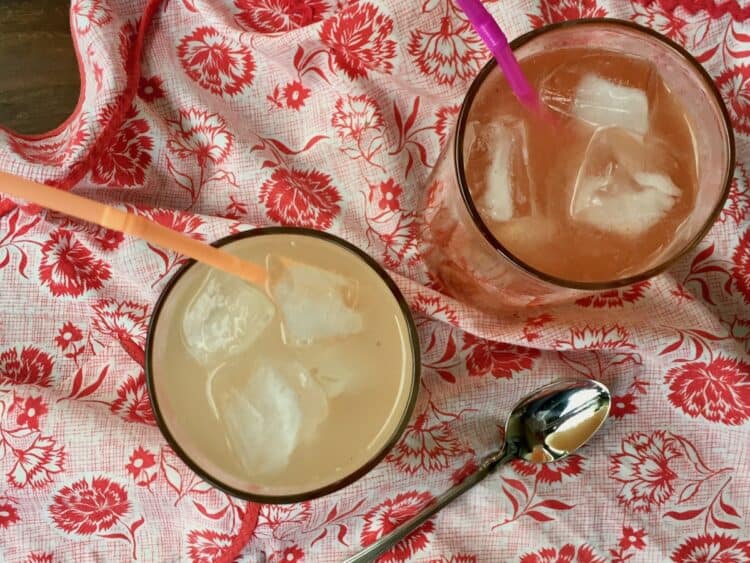 Pear Ginger Shrub in a glass with straw and spoon on a vintage apron.