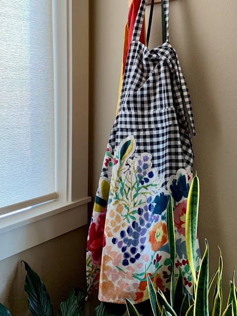 A checked and applique apron hanging on a kitchen hook