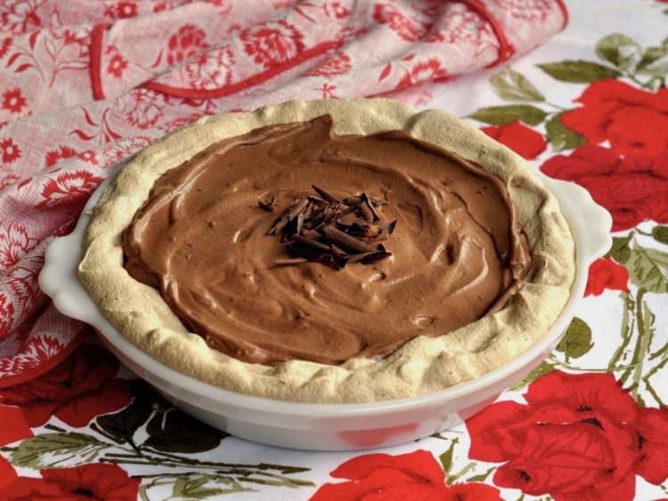 Aunt Hen's Chocolate Angel Pie in white pie plate on vintage tablecloth with vintage apron.