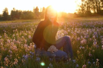 Lisa in a field of wildflowers with the sun setting on the horizon