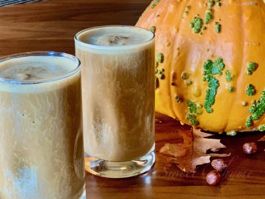 Gingerbread Molasses Smoothies on a wood table with a pumpkin background.