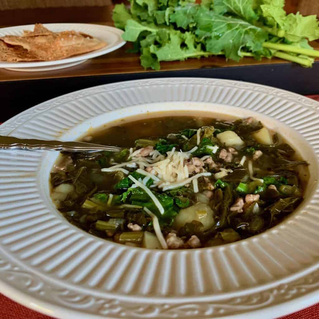 Kale and Potato Soup with Sausage and Balsamic Vinegar in a white bowl.