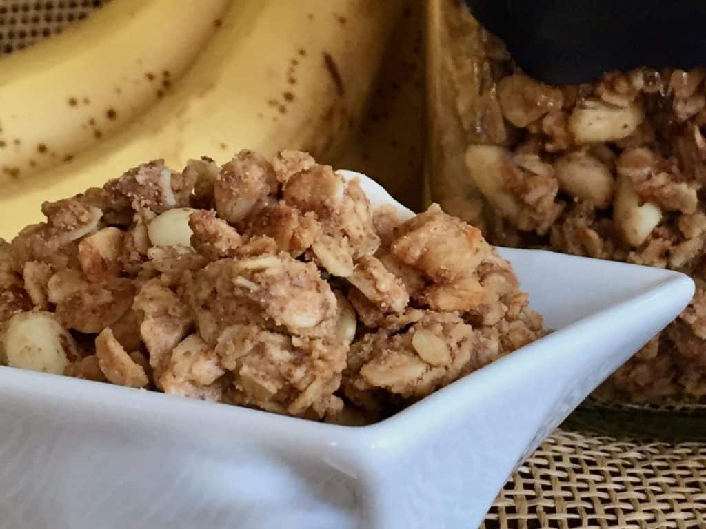 Peanut Butter Banana Granola in a square white dish with jar and bananas.