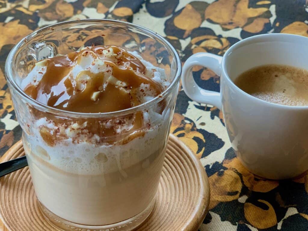 A Peanut Butter Fudge topped latte beside a cup of Espresso.