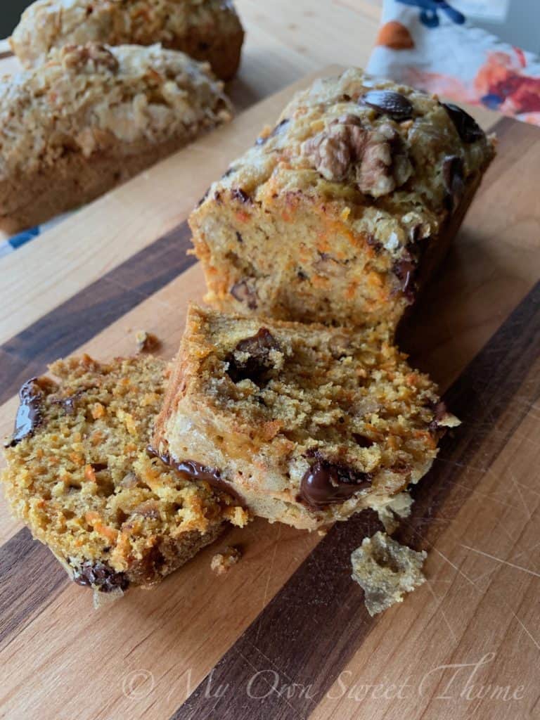 Sugar crusted Carrot Cake Bread topped with chocolate chips, sliced on a wooden cutting board