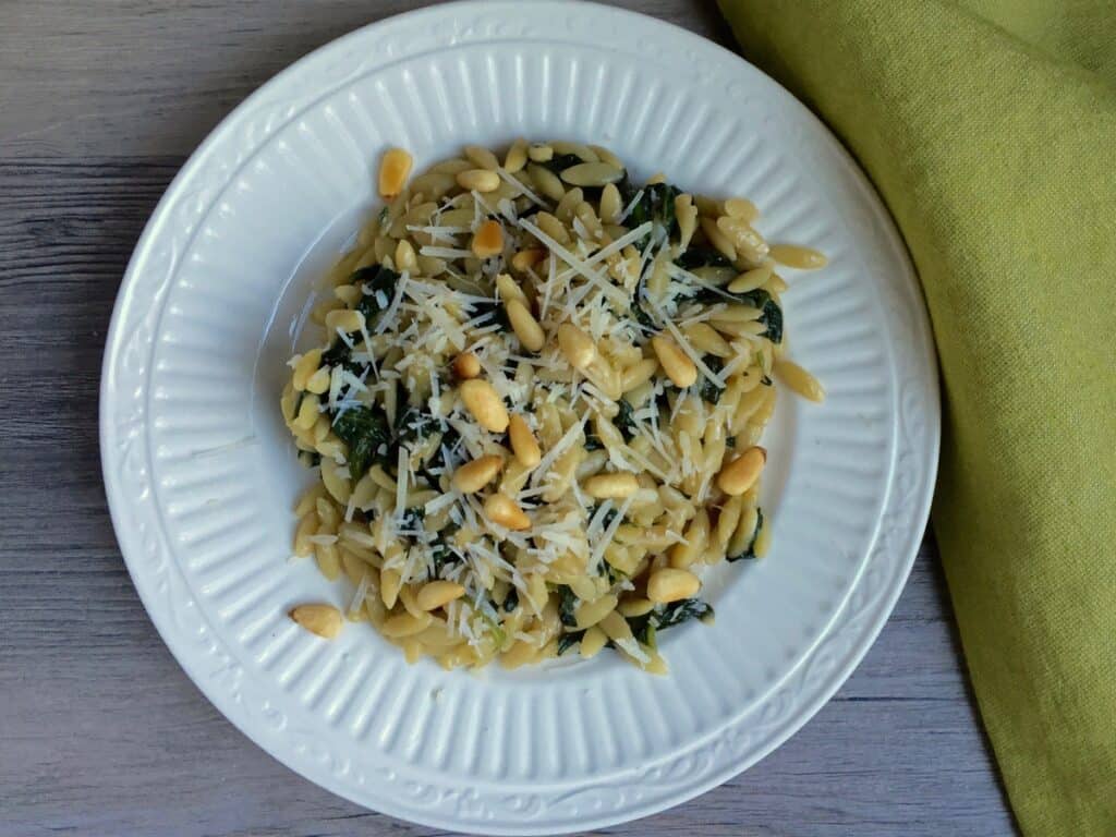 Orzo with Spinach and Pine Nuts garnish with shredded parmesan.