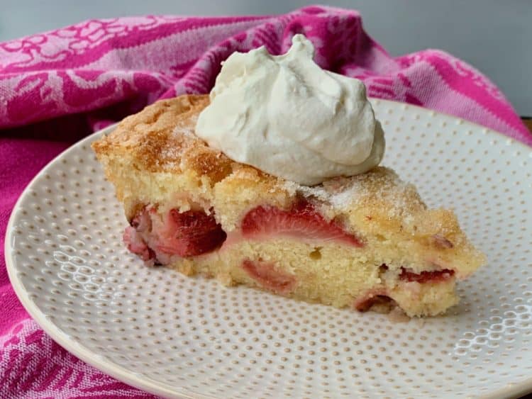 A whipped cream topped slice of All-in-One Strawberry Shortcake on a dotted dessert plate