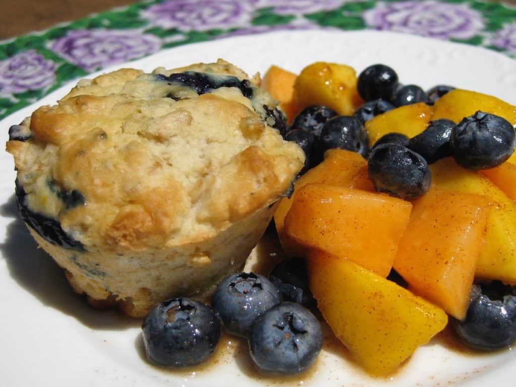 Blueberry Oat Muffin on a plate beside cantaloupe and blueberries
